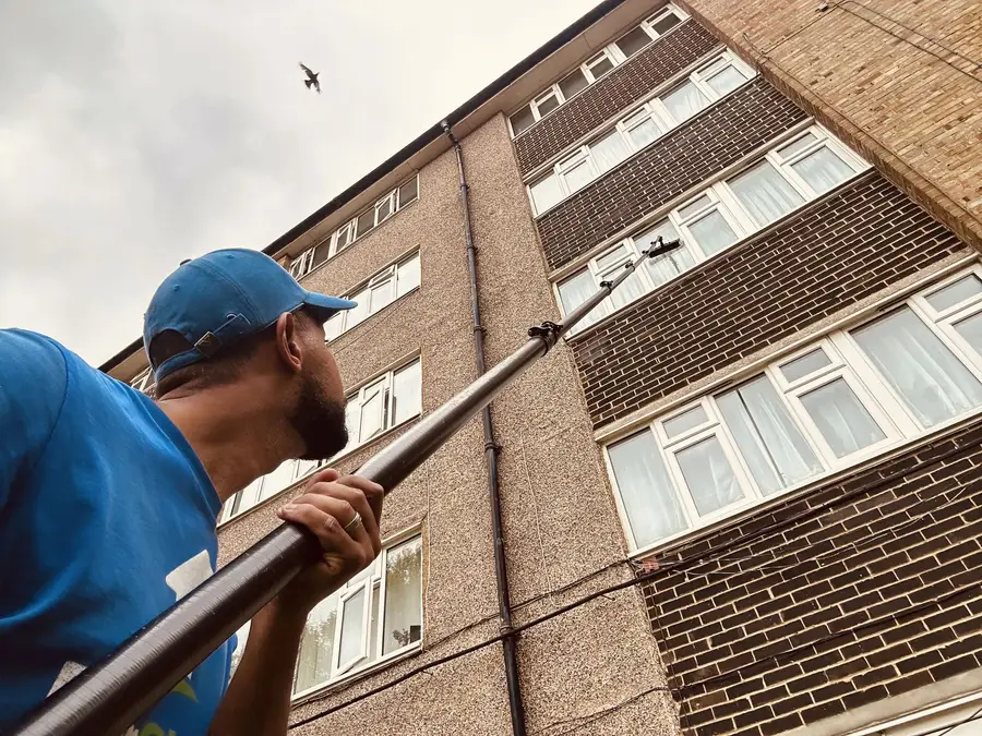 Reaching the upper windows of a block of flats in Hanwell with a long pole