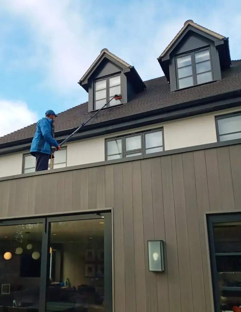 Three-storey house with dormer windows cleaned with a long-reach pole