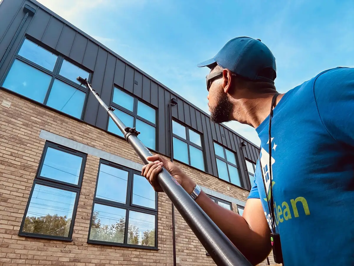 Sebastian in EverClean uniform cleaning upper windows on a new-build with a carbon pole