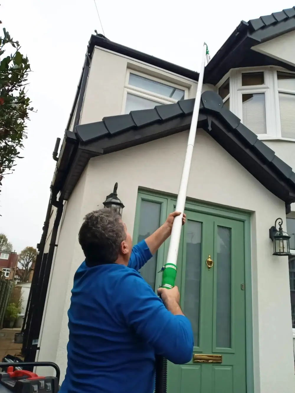 Clearing the gutters of a two-storey house in Perivale from the ground